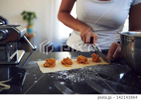 Person, hands and cooking pasta on kitchen counter with knife at home for healthy diet. Woman, chef and food with mixing bowl in closeup for handmade ravioli and preparation of balanced meal Person, hands and cooking pasta on kitchen counter with knife at home for healthy diet. Woman, chef and food with mixing bowl in closeup for handmade ravioli and preparation of balanced meal 142143864