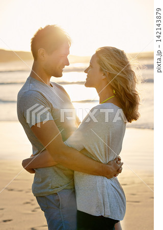 Lens flare, sunset and hug of couple at beach, ocean and sea with affection, bonding and love in summer. People, partners and romance for care together on vacation, holiday and travel in Australia 142143879