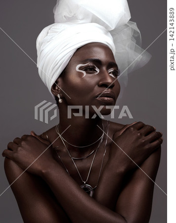 Thinking, wrap and black woman with makeup, beauty and confidence on dark studio background. Face, turban and African model with traditional outfit, eyeshadow cosmetics and necklace for culture pride Thinking, wrap and black woman with makeup, beauty and confidence on dark studio background. Face, turban and African model with traditional outfit, eyeshadow cosmetics and necklace for culture pride 142143889