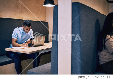 Businessman, reading and writing with phone in diary for research, schedule or reminder on deadline at office cubicle. Man or creative employee taking notes in book with mobile smartphone for tasks Businessman, reading and writing with phone in diary for research, schedule or reminder on deadline at office cubicle. Man or creative employee taking notes in book with mobile smartphone for tasks 142143911