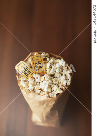 Popcorn, movie tickets and cinema food with event, entertainment and top view for date. Concert, film festival or circus show with corn snack for nutrition, paper bag and vintage coupon at theatre 142144072