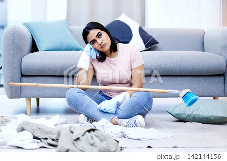 Woman, bored and portrait in living room for cleaning in house with sweeping, dirty clothes and broom. Annoyed, frustrated and moody from housework in home with unhappy for duties on weekend. Woman, bored and portrait in living room for cleaning in house with sweeping, dirty clothes and broom. Annoyed, frustrated and moody from housework in home with unhappy for duties on weekend. 142144156