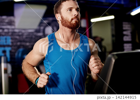 Earphones, exercise and man running on treadmill in gym for health, wellness and body weightloss. Fitness, runner and male athlete with cardio workout on machine for race training in sports center. 142144915