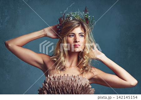 Nature, fashion and creative woman with flowers in crown in hair and clothes with feathers in studio. Natural, style and inspiration from environment for dress in fantasy cosplay or model in costume 142145154