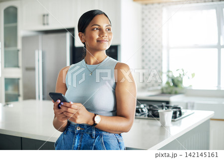 Happy, cellphone and woman in kitchen scroll on mobile app, internet or website at apartment. Smile, phone and young female person networking online and reading email by counter at modern home. 142145161