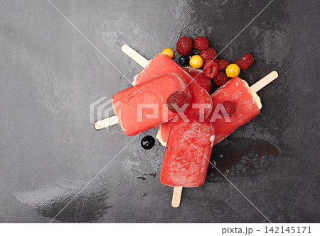 Group, popsicle and fruit by dark background for ice, summer and dessert with blackcurrant. Gooseberry, raspberry and frozen snack with red color on countertop for sorbet, sweet taste and cold food Group, popsicle and fruit by dark background for ice, summer and dessert with blackcurrant. Gooseberry, raspberry and frozen snack with red color on countertop for sorbet, sweet taste and cold food 142145171