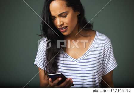 Confused, smartphone and woman in studio for scam, phishing or fake news on green background. Communication, annoyed and person on mobile phone for internet problem, spam email or negative text 142145197