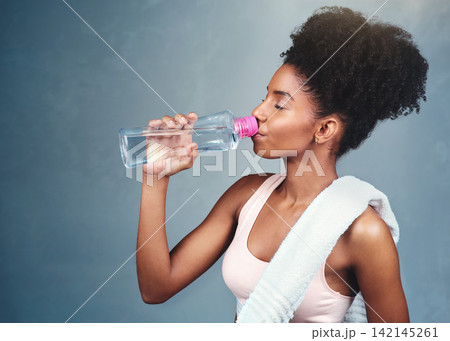 Gym, fitness and woman drinking water in studio for training, workout or intense cardio exercise on grey background. Sports, liquid and thirsty athlete with hydrogen drink for hydration and recovery Gym, fitness and woman drinking water in studio for training, workout or intense cardio exercise on grey background. Sports, liquid and thirsty athlete with hydrogen drink for hydration and recovery 142145261