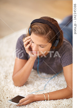 Carpet, headphones or woman with phone for music streaming, subscription or wellness in home. Smile, girl or female person listening to audio, track or song to relax on floor on mobile app for peace Carpet, headphones or woman with phone for music streaming, subscription or wellness in home. Smile, girl or female person listening to audio, track or song to relax on floor on mobile app for peace 142145386