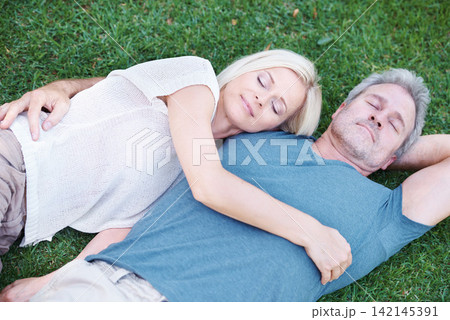 Man, woman and mature or relax on grass for afternoon nap in nature backyard for resting, weekend or sleeping. Couple, embrace and bonding connection with peaceful calm in Australia, meadow or spring Man, woman and mature or relax on grass for afternoon nap in nature backyard for resting, weekend or sleeping. Couple, embrace and bonding connection with peaceful calm in Australia, meadow or spring 142145391