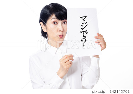 マジで?と書かれた紙を持ち驚いた表情の白いシャツを着た中年女性 マジで?と書かれた紙を持ち驚いた表情の白いシャツを着た中年女性 142145701