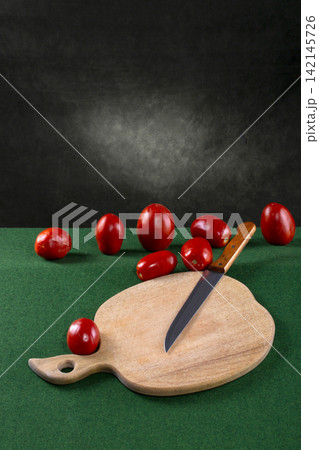 Ripe red tomatoes with a knife and a cutting wooden board 142145726