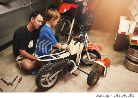 Parent, child and fixing bike in garage at home for teamwork, support and repair with tools. Family man, father and son for bonding, helping and together as mechanic for motorbike in carport 142146309
