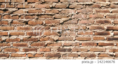 Rough red clay brick wall with thick cement mortar 142146676