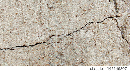 Diagonal cracks on a rough, cream-colored concrete wall. Diagonal cracks on a rough, cream-colored concrete wall. 142146807