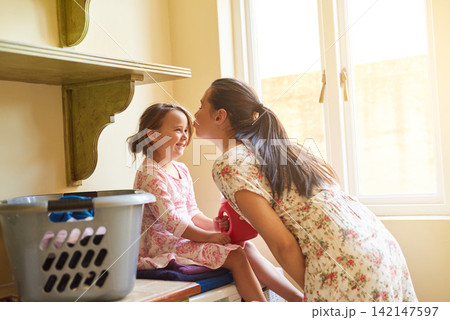 Kiss, mother and girl with clothes for laundry for washing in house, apartment or home for housekeeping and cleanliness. Basket, portrait or happy for chores, working and hygiene or maintenance 142147597