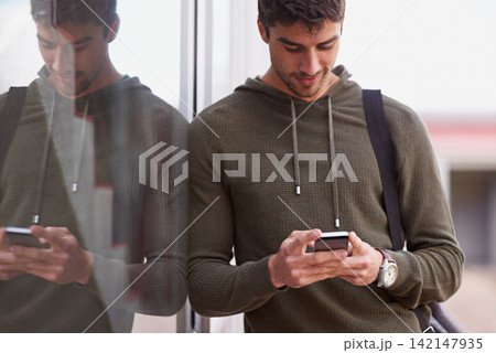 Outdoor, smartphone and man in window reflection, texting and social media for student on campus. Technology, cellphone for scroll for male learner, internet or conversation online for entertainment 142147935