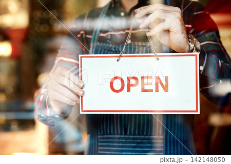Open, sign and person at window of cafe for small business, information and start of service. Coffee shop, hospitality and waiter with board by glass for restaurant, message and beginning of work day 142148050