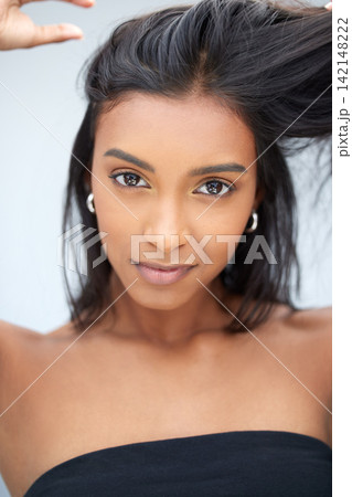 Scalp, hair care and portrait of Indian woman for natural growth, cosmetics and confidence. Results, girl and face of model in studio on blue background for conditioner, texture and trendy style Scalp, hair care and portrait of Indian woman for natural growth, cosmetics and confidence. Results, girl and face of model in studio on blue background for conditioner, texture and trendy style 142148222