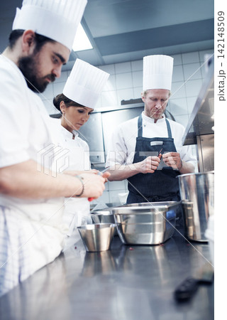 Food, team and chef in kitchen for catering service, fine dining or delicious dish. Hospitality, equipment and group of employees with knife for cooking meal, preparation or dinner rush in restaurant Food, team and chef in kitchen for catering service, fine dining or delicious dish. Hospitality, equipment and group of employees with knife for cooking meal, preparation or dinner rush in restaurant 142148509