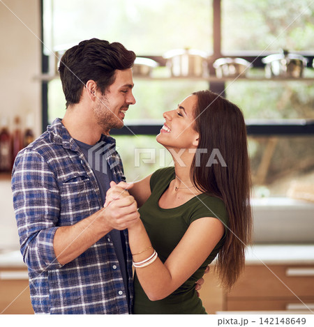 Happy, young couple and dancing together in kitchen for bonding, fun and romantic connection at home. Excited, man and woman with smile for holding hands, love and trust with rhythm in new apartment Happy, young couple and dancing together in kitchen for bonding, fun and romantic connection at home. Excited, man and woman with smile for holding hands, love and trust with rhythm in new apartment 142148649