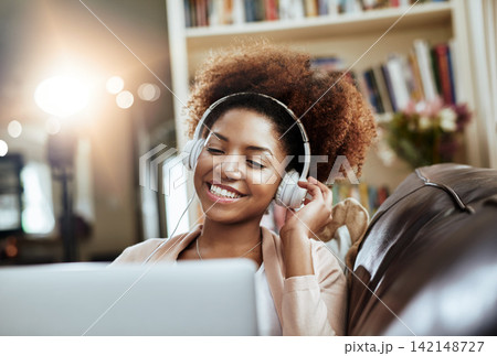 Smile, laptop and woman on sofa with headphones, relax and happy morning streaming in living room. Rest, wellness and girl on couch in home with online music, digital app and computer in apartment. Smile, laptop and woman on sofa with headphones, relax and happy morning streaming in living room. Rest, wellness and girl on couch in home with online music, digital app and computer in apartment. 142148727