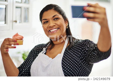 Baker, happy woman and selfie of dessert in kitchen for cooking, show sweets and online blog post in home. Pastry, cupcake and photography for social media, food influencer or smile of chef in house 142149079