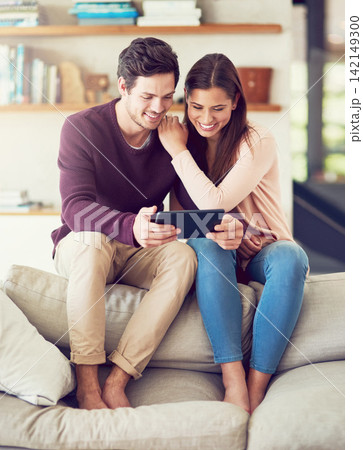 Smile, couple and relax on sofa with tablet for social media, news or streaming video together. Digital technology, man and woman in living room for online shopping or reading blog on app in home 142149300