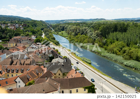 High angle panorama of Austrian village with tile roofs along a riverbank 142150025