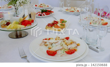 Elegantly set dining table with gourmet appetizers including caesar salad, bruschetta, cheese and fruit platters, highlighting festive social gathering ambiance Elegantly set dining table with gourmet appetizers including caesar salad, bruschetta, cheese and fruit platters, highlighting festive social gathering ambiance 142150688