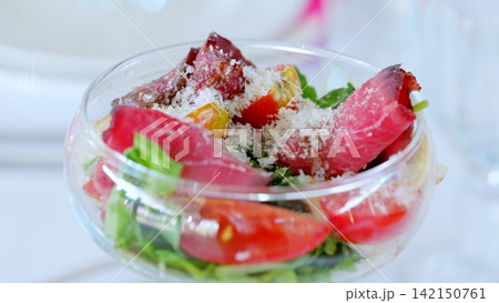 Festive glass dish displaying colorful salad, vibrant tomatoes, crisp arugula, thin dried meat slices, sprinkled parmesan cheese Festive glass dish displaying colorful salad, vibrant tomatoes, crisp arugula, thin dried meat slices, sprinkled parmesan cheese 142150761