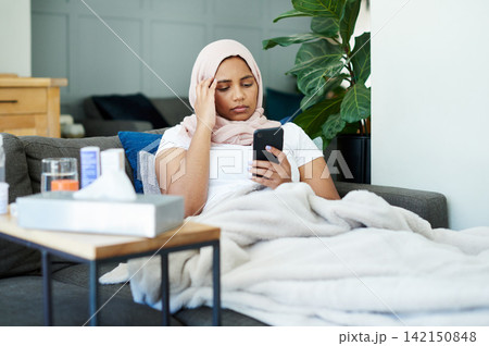 Woman, muslim and phone for headache in home, cold and medicine for illness and treatment for health. Female person, hijab and migraine on couch for burnout, pills and stress for crisis or head pain 142150848
