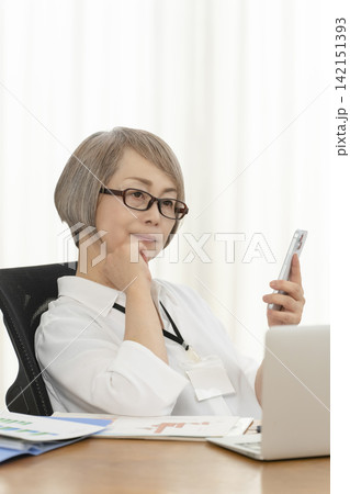 オフィスで仕事をするシニア女性 オフィスで仕事をするシニア女性 142151393