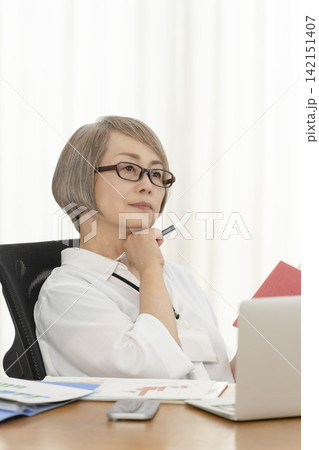 オフィスで仕事をするシニア女性 オフィスで仕事をするシニア女性 142151407