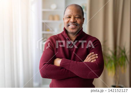 Confident mature Black man standing at home with arms crossed 142152127