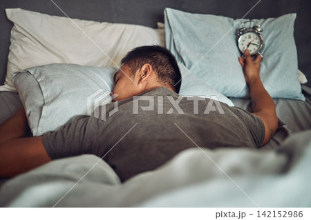 Man, sleeping and bed with alarm clock or tired insomnia for bad time management, depression or dreaming. Male person, pillow and lazy snooze in home or overworked burnout, mental health or Monday Man, sleeping and bed with alarm clock or tired insomnia for bad time management, depression or dreaming. Male person, pillow and lazy snooze in home or overworked burnout, mental health or Monday 142152986