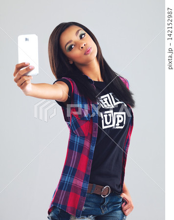 Selfie, fashion and woman with mobile phone in studio for photography, social media or profile picture on gray background. kiss, gen z and girl with smartphone for edgy, trendy or stylish clothing Selfie, fashion and woman with mobile phone in studio for photography, social media or profile picture on gray background. kiss, gen z and girl with smartphone for edgy, trendy or stylish clothing 142152987