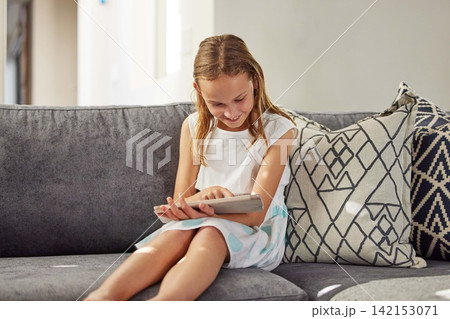 Happy, home and girl on couch, tablet and typing for games, social media and online cartoon. Apartment, child development or kid with tech, internet or digital app with network, smile or reading book 142153071