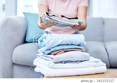 Folding laundry, person and hands in living room on couch, cotton and fabric clothing. Organizing washing, housekeeper and spring cleaning in lounge for routine, wellness and morning on home sofa Folding laundry, person and hands in living room on couch, cotton and fabric clothing. Organizing washing, housekeeper and spring cleaning in lounge for routine, wellness and morning on home sofa 142153127