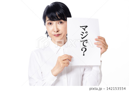 マジで?と書かれた紙を両手で持ち嬉しさを隠せない白いシャツを着た中年女性 マジで?と書かれた紙を両手で持ち嬉しさを隠せない白いシャツを着た中年女性 142153554