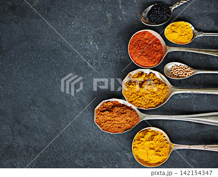 Spoon, powder and group of spices by dark background for cooking dinner, health and nutrition. Turmeric, chilli and seeds on black surface with zoom for Oriental food, antioxidant and spicy cuisine Spoon, powder and group of spices by dark background for cooking dinner, health and nutrition. Turmeric, chilli and seeds on black surface with zoom for Oriental food, antioxidant and spicy cuisine 142154347