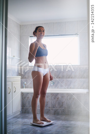 Weight loss, woman and happy in bathroom on scale with yes, proud and standing in underwear for goals. Female person, success and diet at home for nutrition, fitness and achievement or checking BMI Weight loss, woman and happy in bathroom on scale with yes, proud and standing in underwear for goals. Female person, success and diet at home for nutrition, fitness and achievement or checking BMI 142154355
