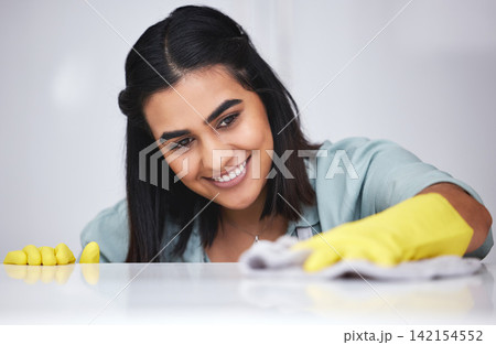 Indian woman, happy or cleaner with spray bottle for table, kitchen counter or dirty furniture in home. Smile, maid or janitor washing messy surface with product, liquid soap or cloth with gloves 142154552