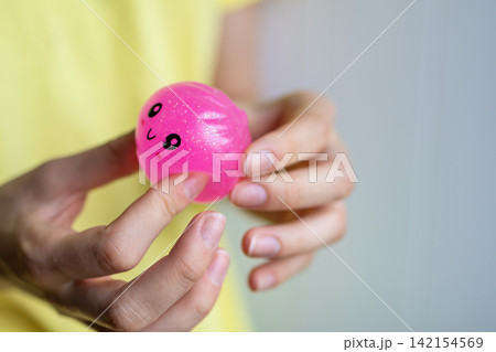 Close-up of hands holding a pink squishy toy before squeezing during sensory play. Concept of stress relief, tactile activity, relaxation and emotional balance. Close-up of hands holding a pink squishy toy before squeezing during sensory play. Concept of stress relief, tactile activity, relaxation and emotional balance. 142154569