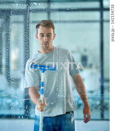 Man, cleaning and window in office building as janitor with squeegee tool for hygiene service, glass or bacteria. Male person, soap and disinfection in corporate workplace or washing, dust or germs Man, cleaning and window in office building as janitor with squeegee tool for hygiene service, glass or bacteria. Male person, soap and disinfection in corporate workplace or washing, dust or germs 142154738