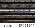 A close-up of a car tire tread, revealing a detailed view of the rubber pattern. Macro photography of the tread of a new car tire, showing a clearly defined pattern. 142154909