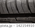 A close-up of a car tire tread, revealing a detailed view of the rubber pattern. Macro photography of the tread of a new car tire, showing a clearly defined pattern. 142154910