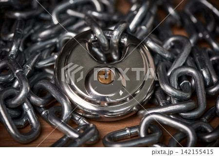 Security, steel and chain with lock for safety on wooden surface for privacy or protection. Metal, equipment and iron padlock and link shackles on table for password or guard with key for secret. Security, steel and chain with lock for safety on wooden surface for privacy or protection. Metal, equipment and iron padlock and link shackles on table for password or guard with key for secret. 142155415