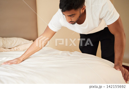 Home, man and bed with cleaning in morning for maintenance, daily routine or change of duvet. Furniture, mattress and male person with housekeeping in bedroom for fresh fabric, wellness and hygiene 142155692