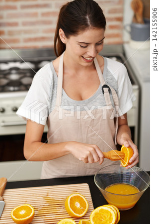 Nutritionist, in kitchen and fresh orange juice in bowl for healthy drink, vitamin C or organic snack. Woman, in apron and making delicious citrus liquid for natural treat, baking cake or new diet 142155906